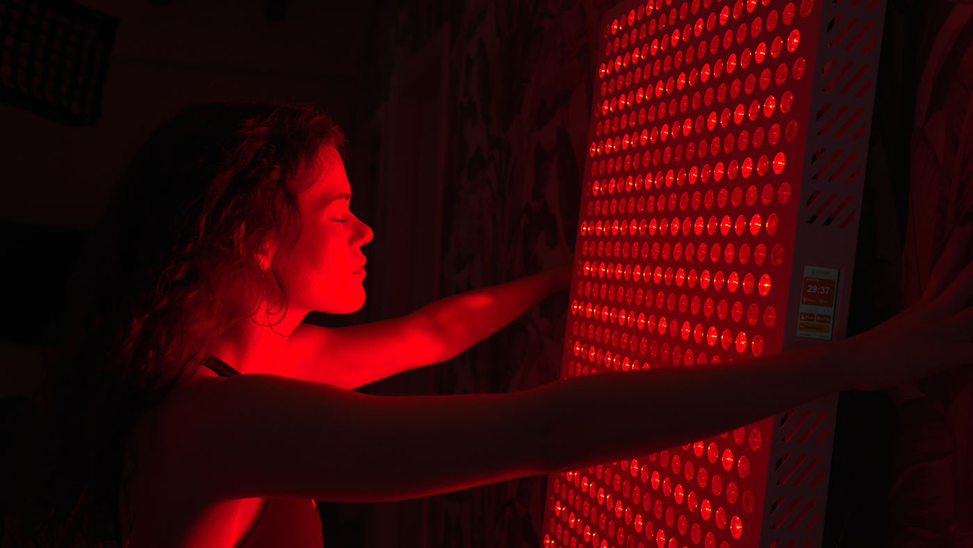 Full Body Red Light Therapy - this image shows a ladey close to a red light therapy panel with her eyes closed